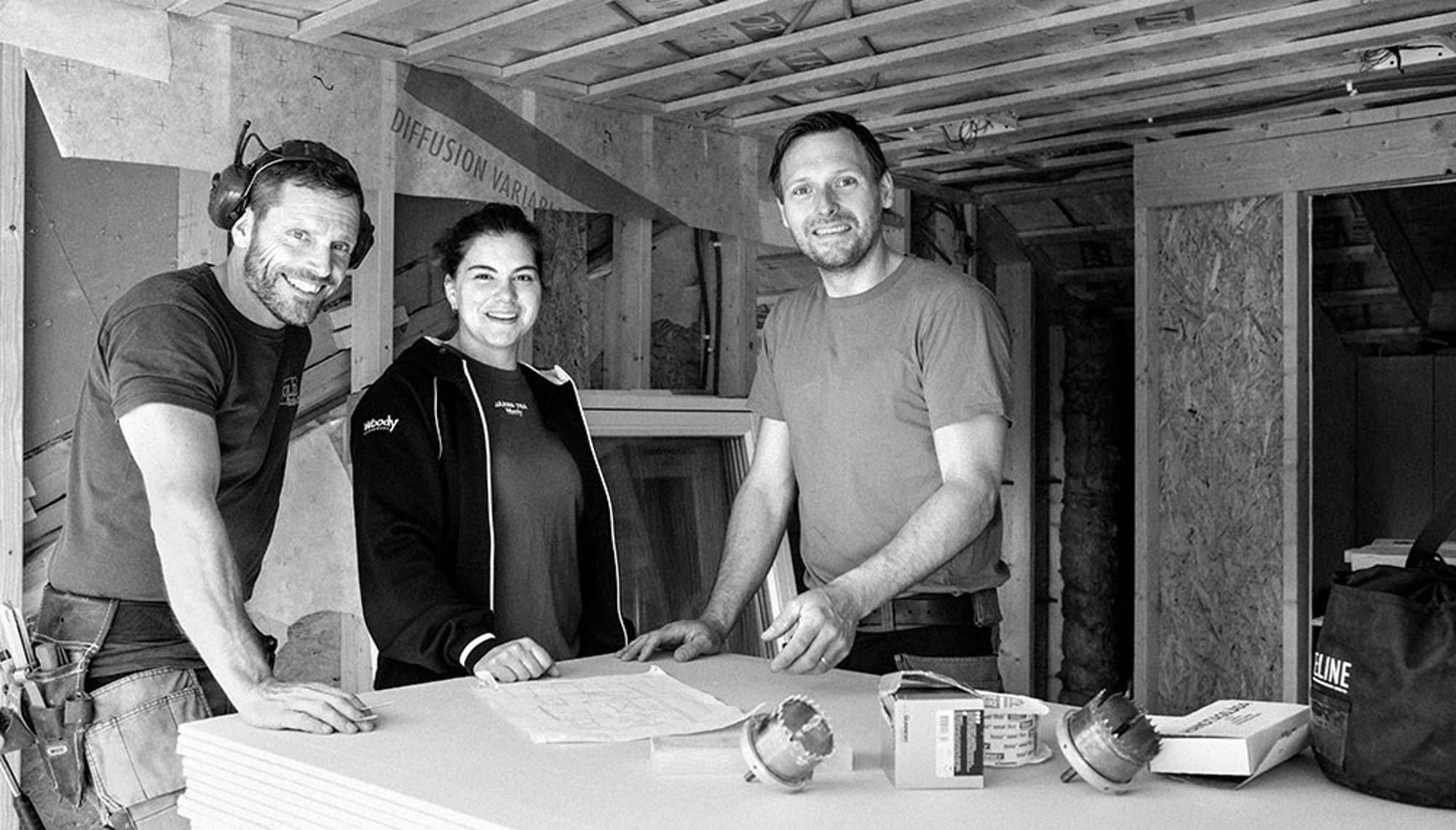 nomenu Bild på två män och en kvinna från Woody som står framför en arbetsmiljöplan