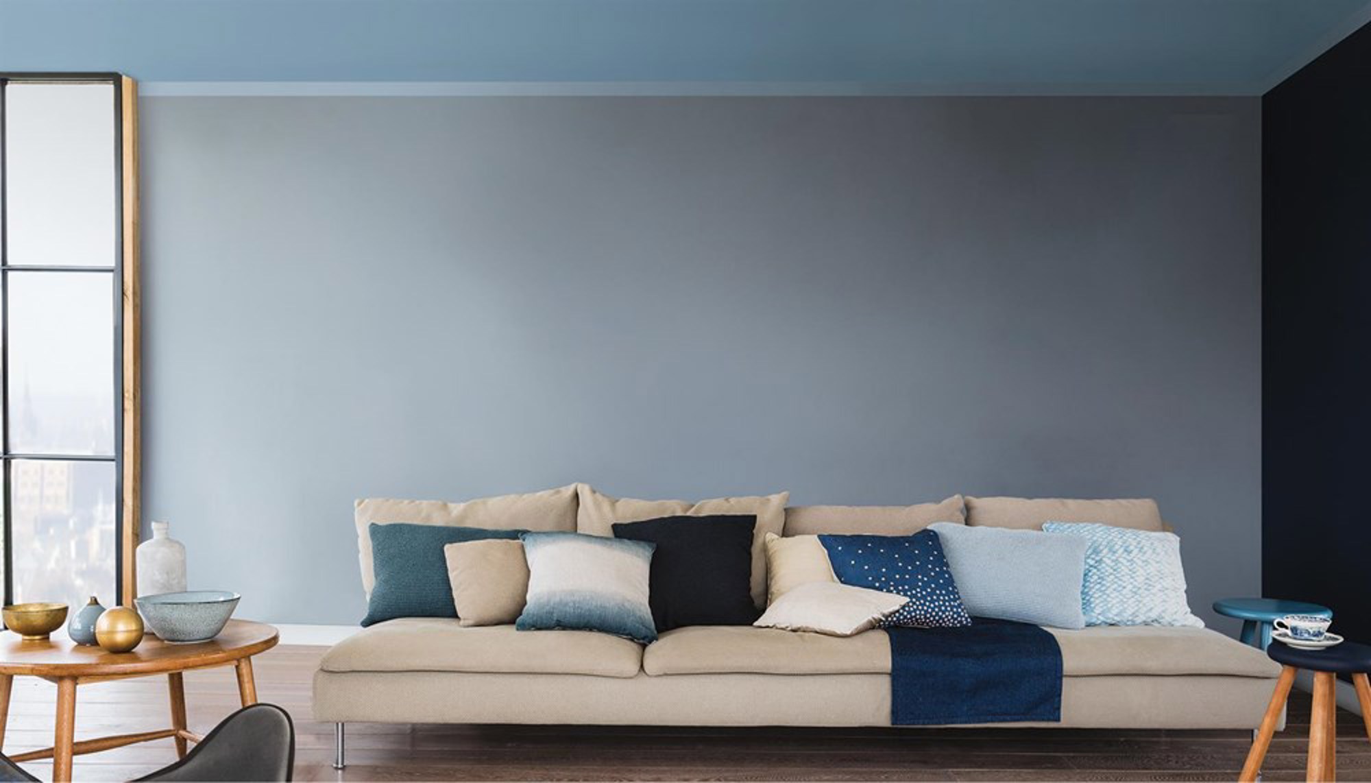 nomenu Bild av blå vägg med en beige soffa framför med många kuddar i 