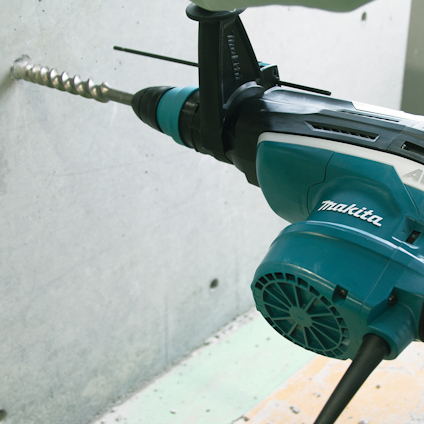 Borrmaskin av märket Makita borrar i en betongvägg.