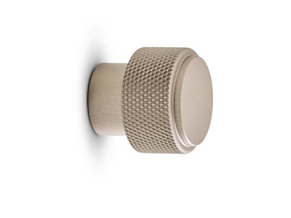 Metallknopp med sandfärg, räfflad greppyta och slät, rund topp.