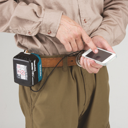 En person pekar på en smartphone med ett verktygsbatteri fäst vid bältet.