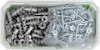 Plastlåda med metallskruvar och pluggar, delvis förpackade i plastpåsar.