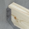 Träkonstruktionsbalk fastsatt i en metallbeslag med bultar mot en betongvägg.