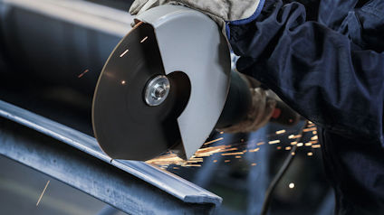 Person använder slipmaskin på metall, gnistor flyger.