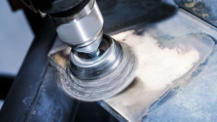 Borrmaskin med slipskiva slipar en metallisk yta.