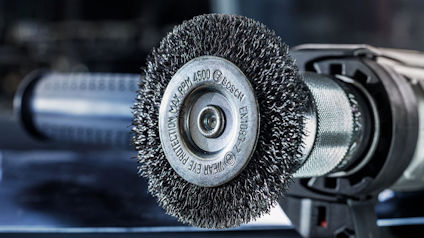 Stålborste på en vinkelslip med etikett "BOSCH" och specifikationer.