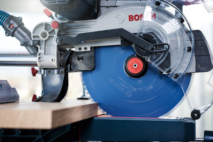 Cirkelsåg med blått sågblad, delvis täckt skydd och Bosch-logotyp, sågar genom träbit.