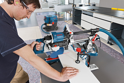 Person använder en stationär såg inomhus, med skyddsglasögon och öronproppar.