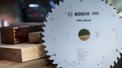 Sågklinga märkt "Bosch PRO Wood" med träplankor i bakgrunden.