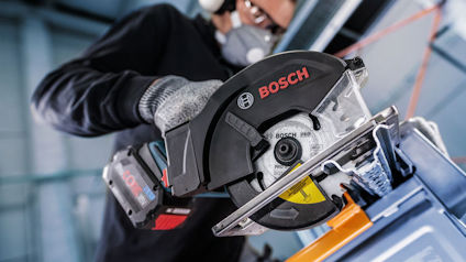 En person använder en cirkelsåg från Bosch. Personen bär skyddshandskar och hörselskydd.