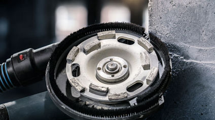 Slipmaskin med rund slipskiva vid sidan av en betongvägg.