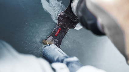 Närbild på en person som sågar genom ett blått rör med en elektrisk såg med Bosch-blad.