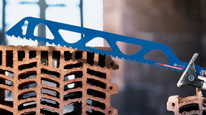 Blå såg med ett tandat blad vilande på ett murblock med ihålig struktur.