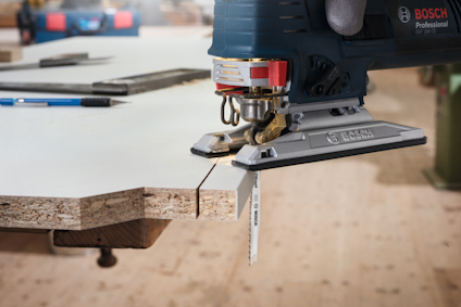 Sticksåg som skär genom träskiva, Bosch Professional märke synligt.