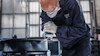 Person i skyddsutrustning svetsar metall i industrimiljö.