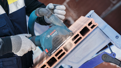 En person i skyddskläder använder en Bosch elektrisk verktyg för att bearbeta tegelblock.