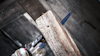 Handsåg sågar genom ett träplank, träflisor flyger åt sidan.