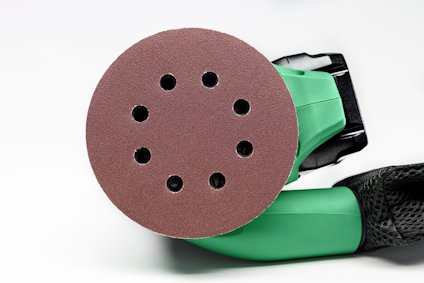 Rund slipmaskin med sandpapper och lufthål, delvis grön handtag, svart bakgrund.