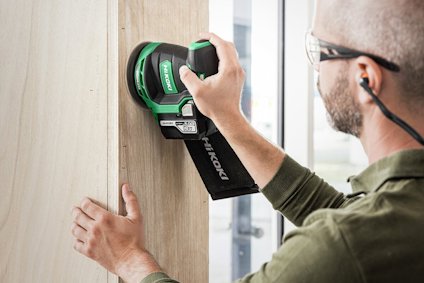 Person som använder en Hitachi sladdlös slipmaskin på en träyta.
