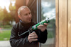 Man using a caulk gun to apply sealant to a wooden structure outdoors.