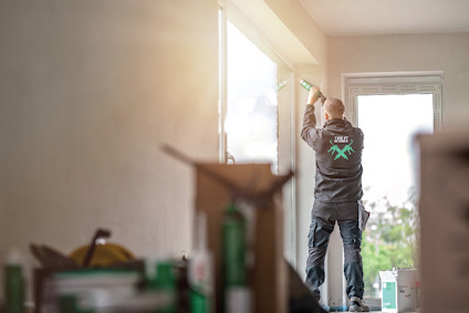 Person i arbetskläder applicerar tätning i fönsterspringa med skum.