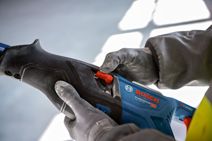 Person håller i en blå och svart Bosch Power Tools maskin med en röd knapp.